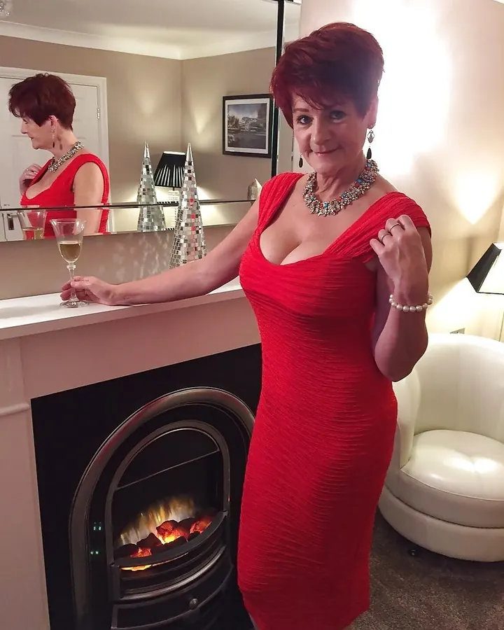 Femme rousse en robe noire, posant dehors, regardant vers le côté