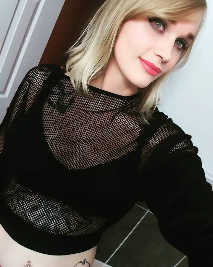 Jeune femme blonde en haut noir transparent, souriante, regardant l'appareil