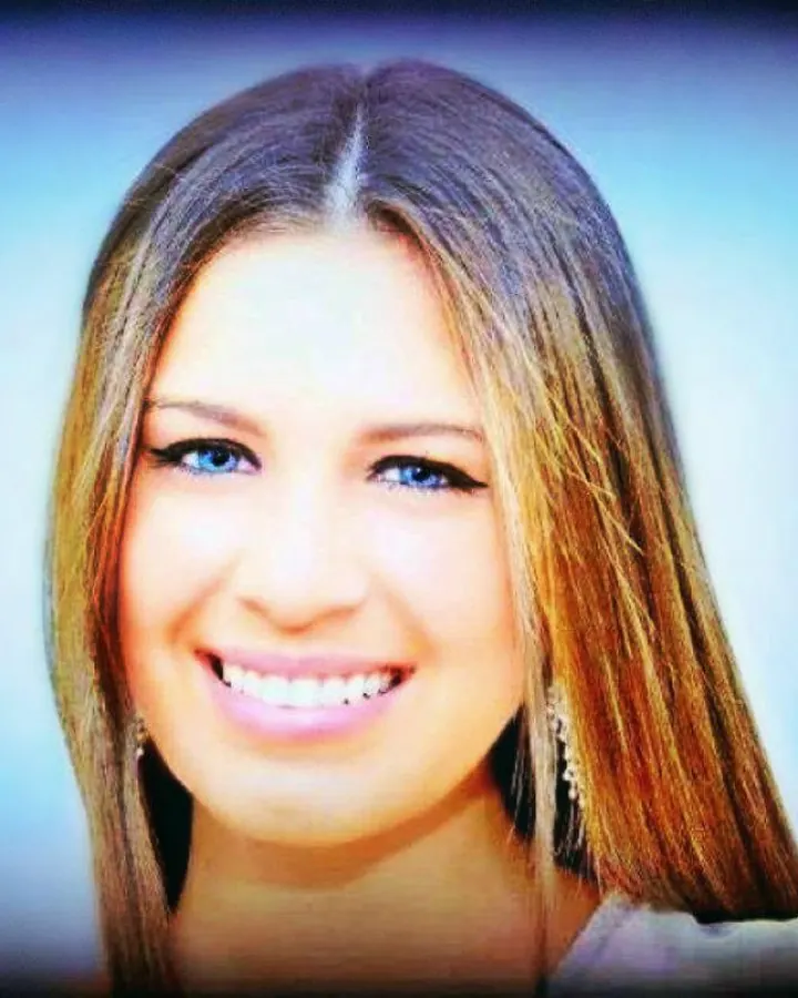 Portrait de femme souriante aux cheveux bruns et yeux bleus, fond flou bleu