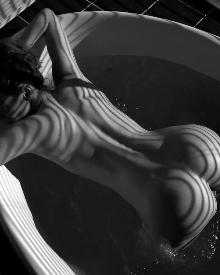 Femme en maillot de bain noir, se tenant les seins dans un bain à remous