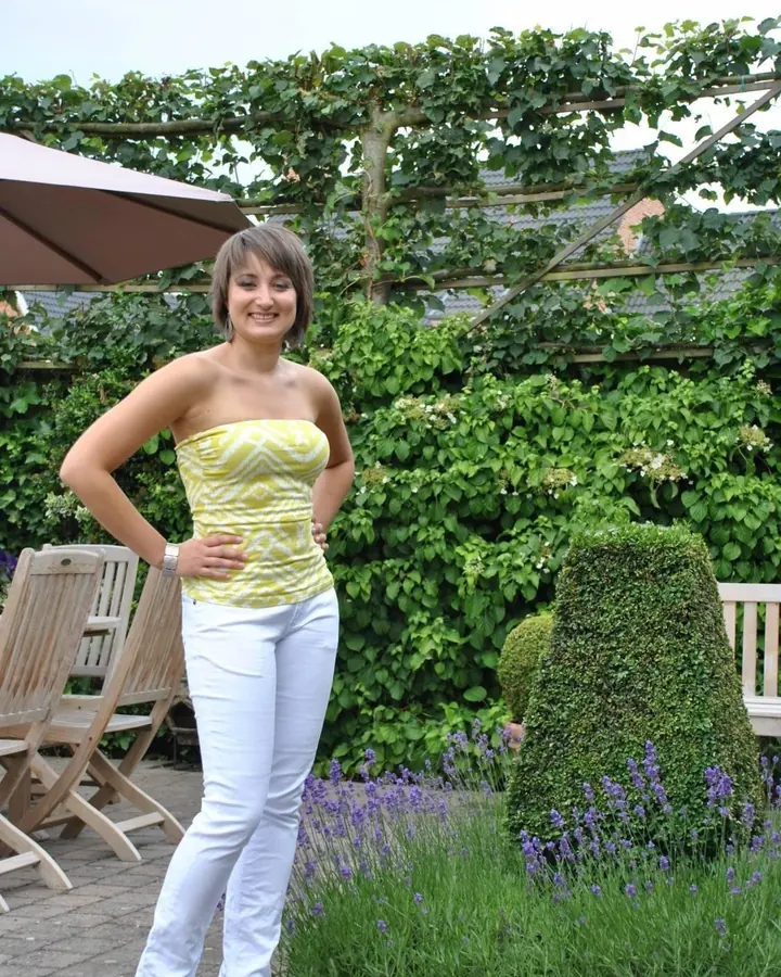Femme aux cheveux châtains courts, vêtue d'un haut noir, regardant l'appareil, souriant légèrement.