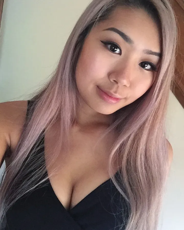 Femme aux cheveux gris clair, en haut noir, souriant à l'appareil photo.