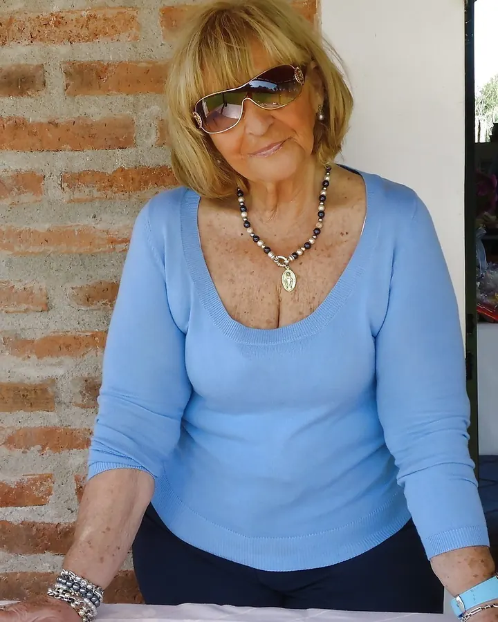 Femme aux cheveux blonds, en robe bleue, posant sur un escalier en colimaçon.