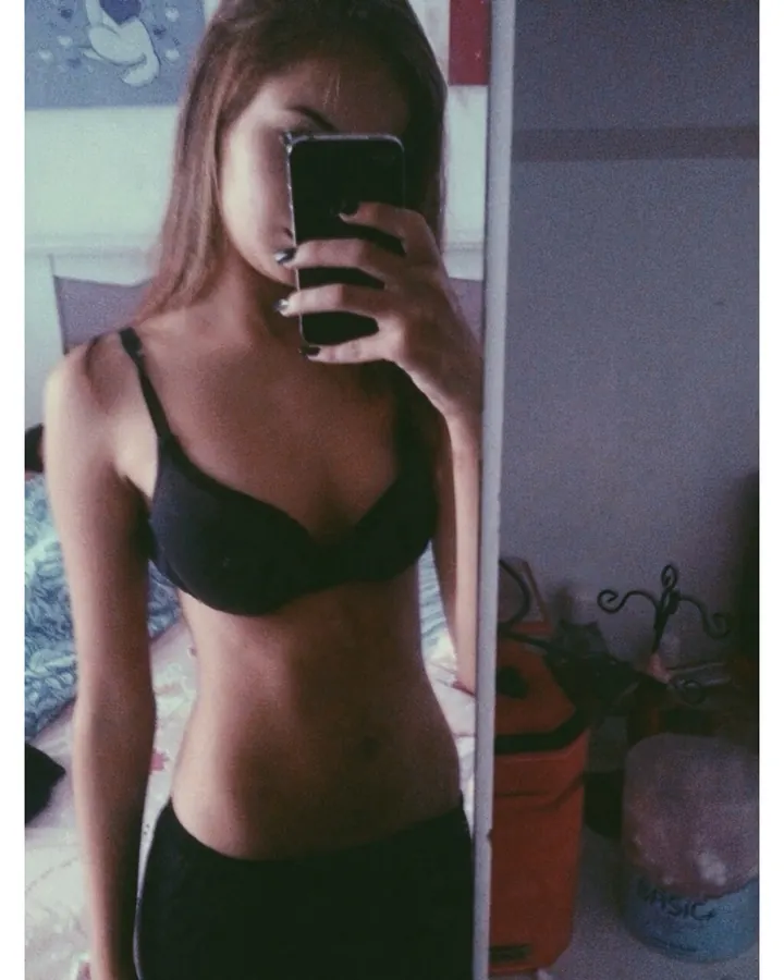 Femme aux cheveux bruns, en bikini rouge, posant de profil dans un parc arboré.