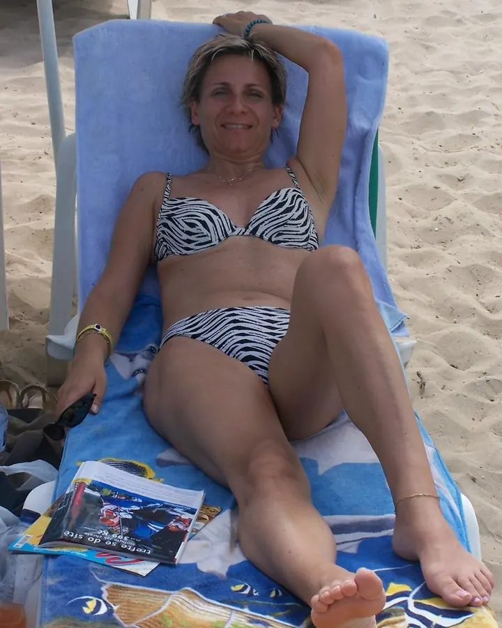 Femme blonde en maillot de bain zèbre, allongée sur une chaise longue à la plage