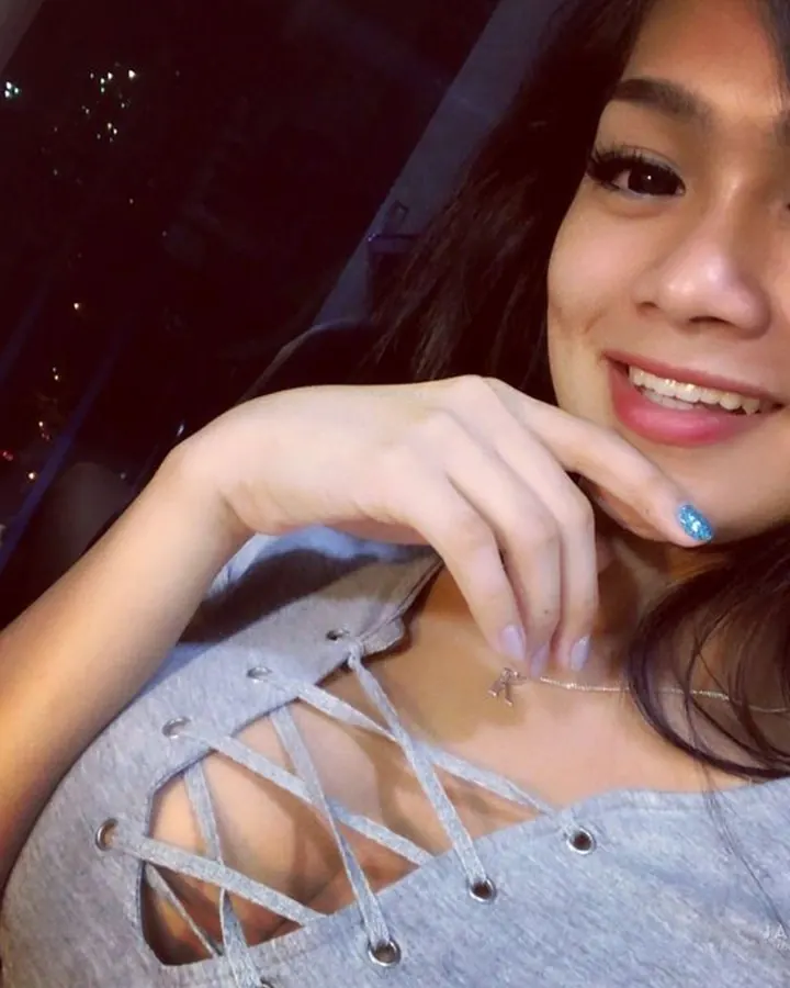 Femme latino aux cheveux châtains, en lingerie grise, prenant un selfie dans un miroir.