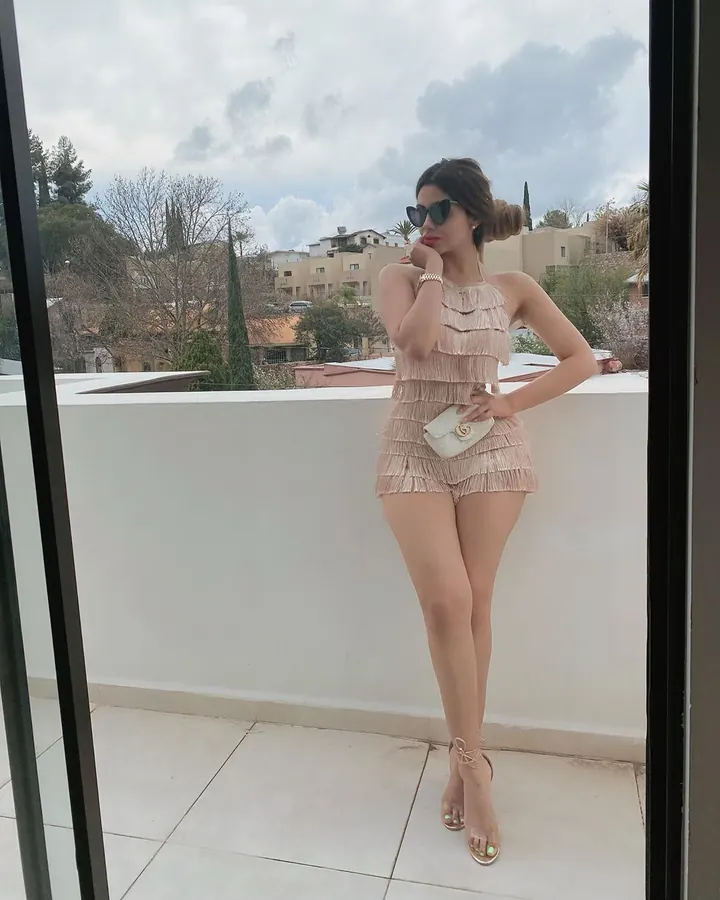 Femme en bikini bleu, posant dans une pièce blanche, pieds nus, regardant l'appareil