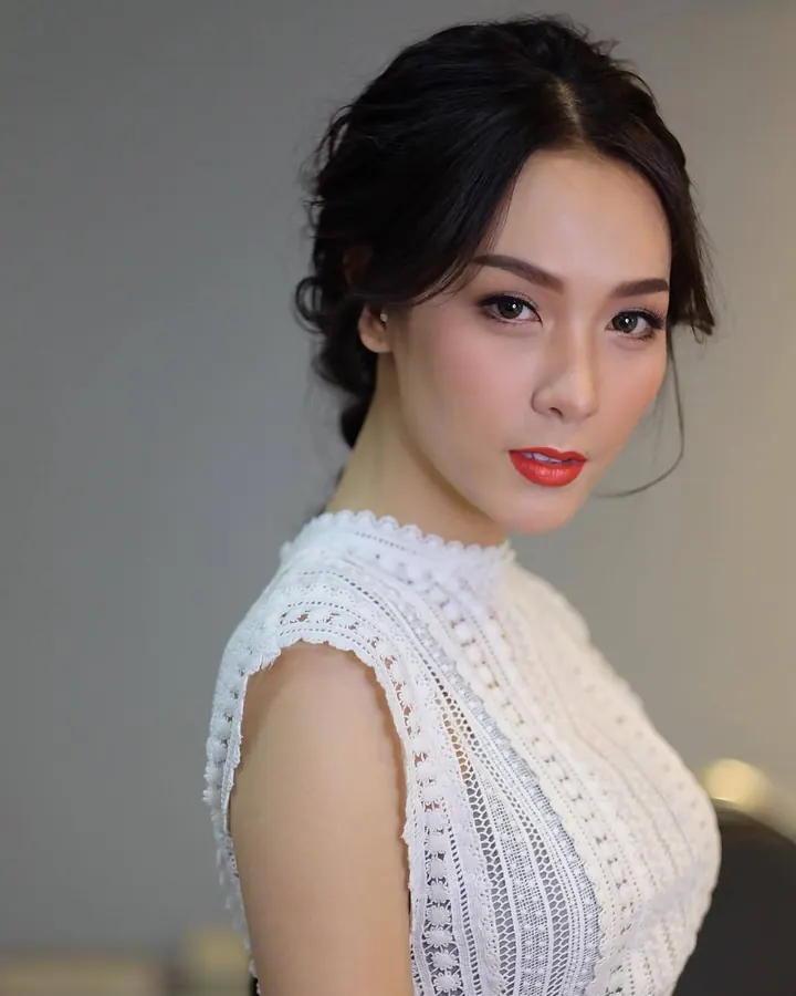 Femme asiatique aux cheveux noirs portant une robe blanche en dentelle, regardant vers l'appareil photo