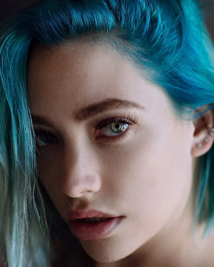 Portrait d'une jeune femme aux cheveux bruns foncés et yeux verts, avec une coupe courte, regardant directement l'objectif.