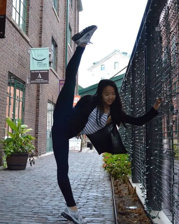 Femme en tenue de sport, effectuant une extension, dans une rue pavée.