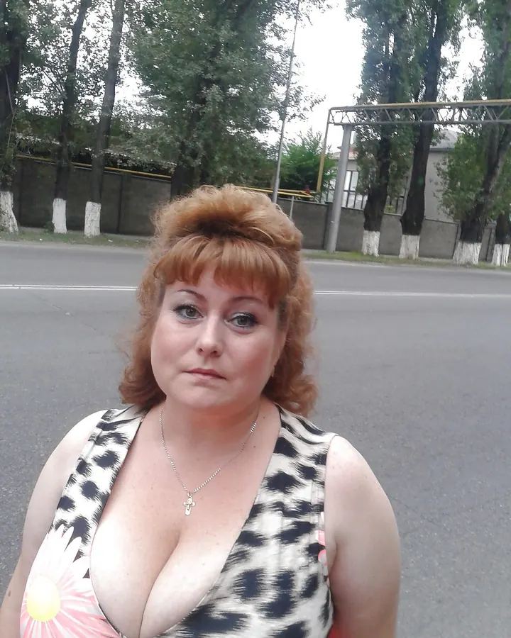 Femme rousse en haut imprimé marguerite, décolleté marqué, regard neutre